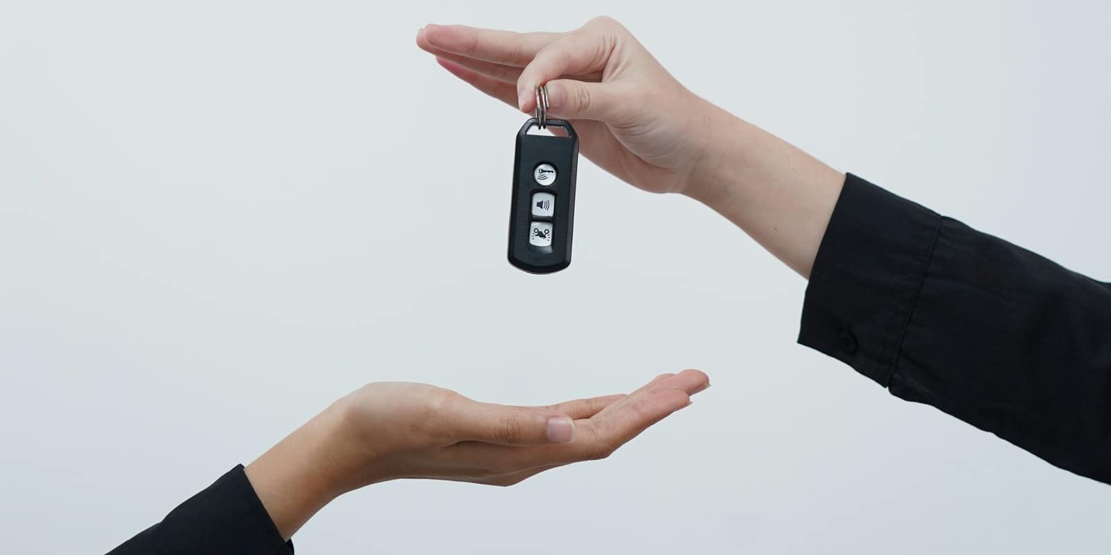 One hand passing a key fob down into another hand