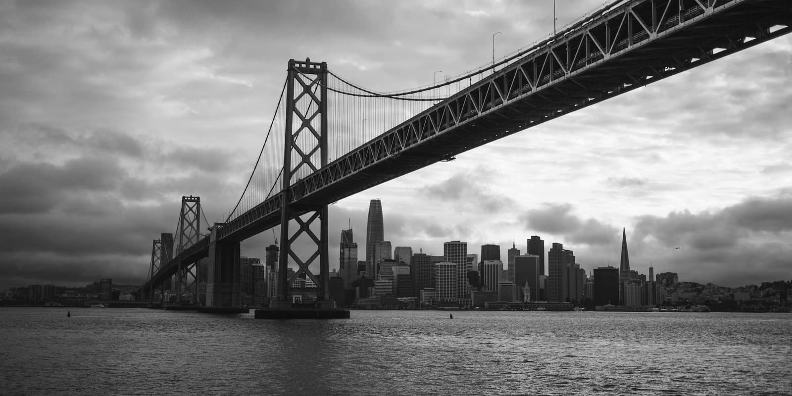 Grayscale photo of a bridge over water