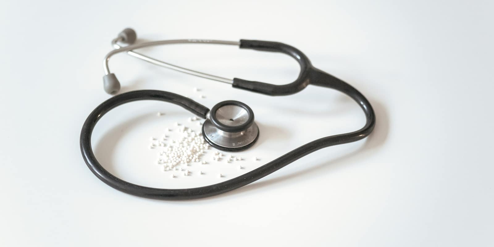 A black and silver stethoscope coiled on a white surface