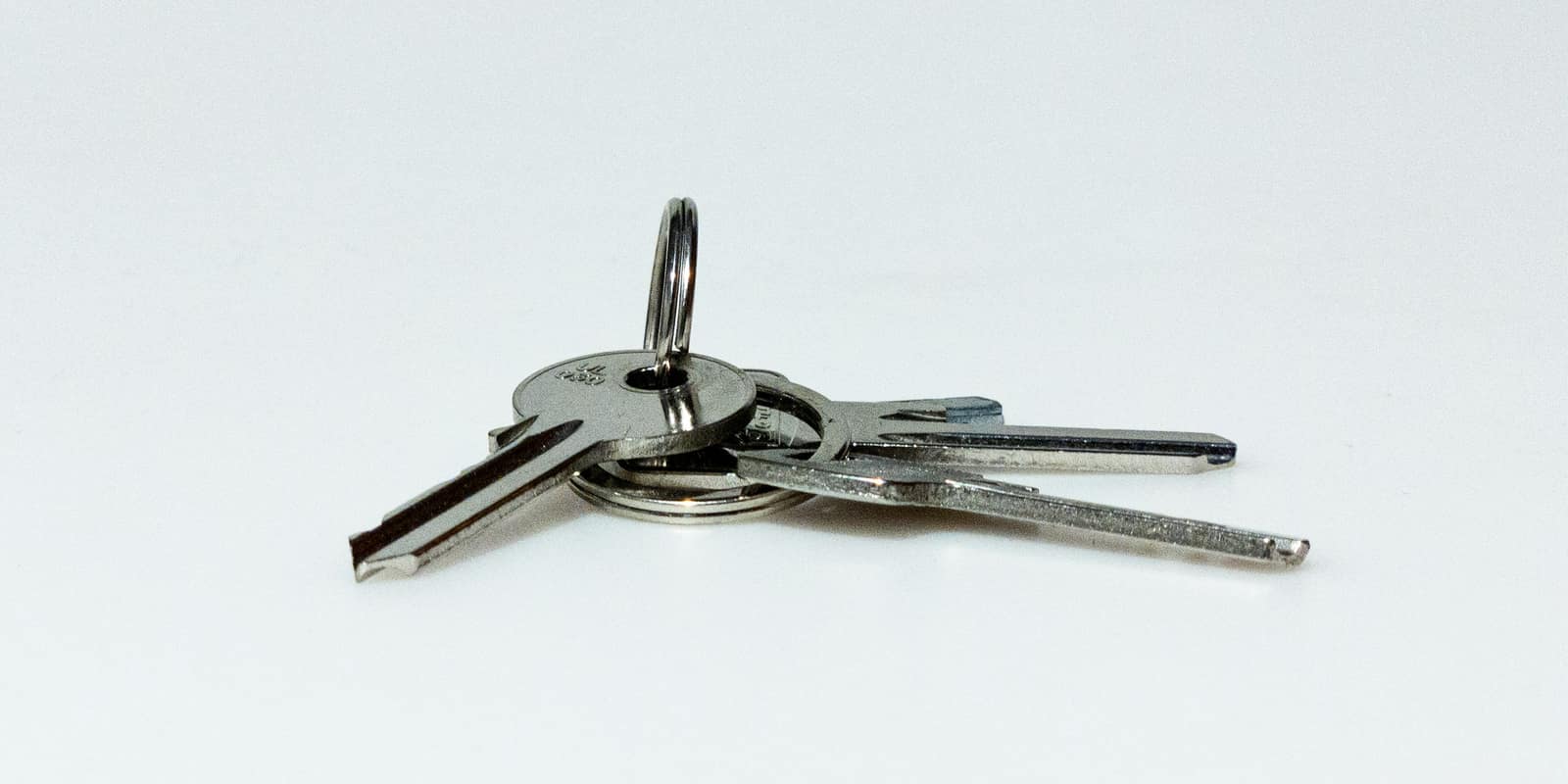 Three silver keys on a ring, lying on a white surface
