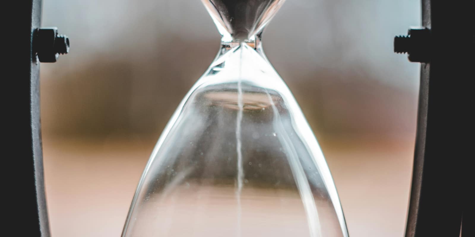 A glass hourglass with sand running through its neck