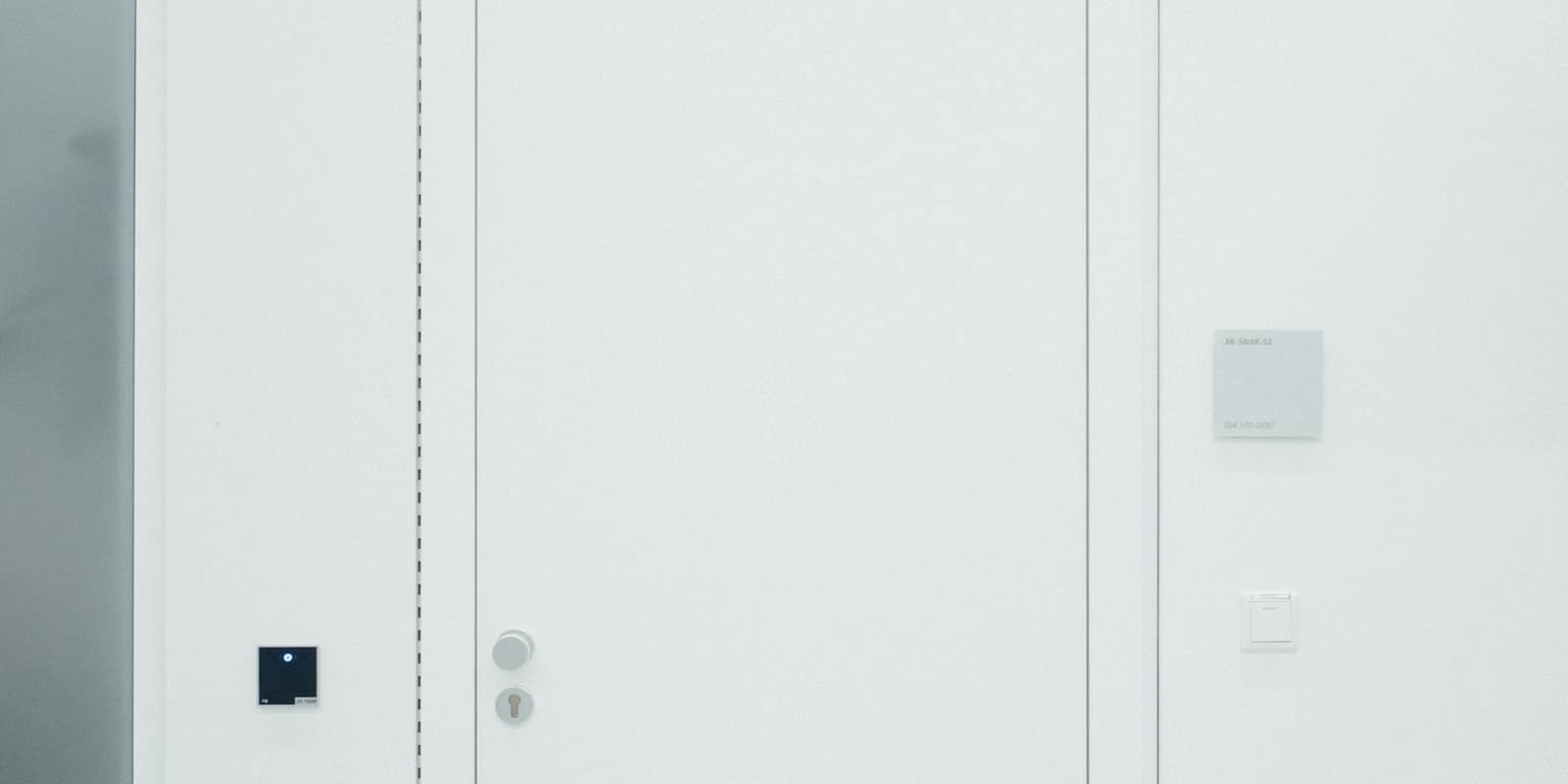 A row of closed white doors in a white wall