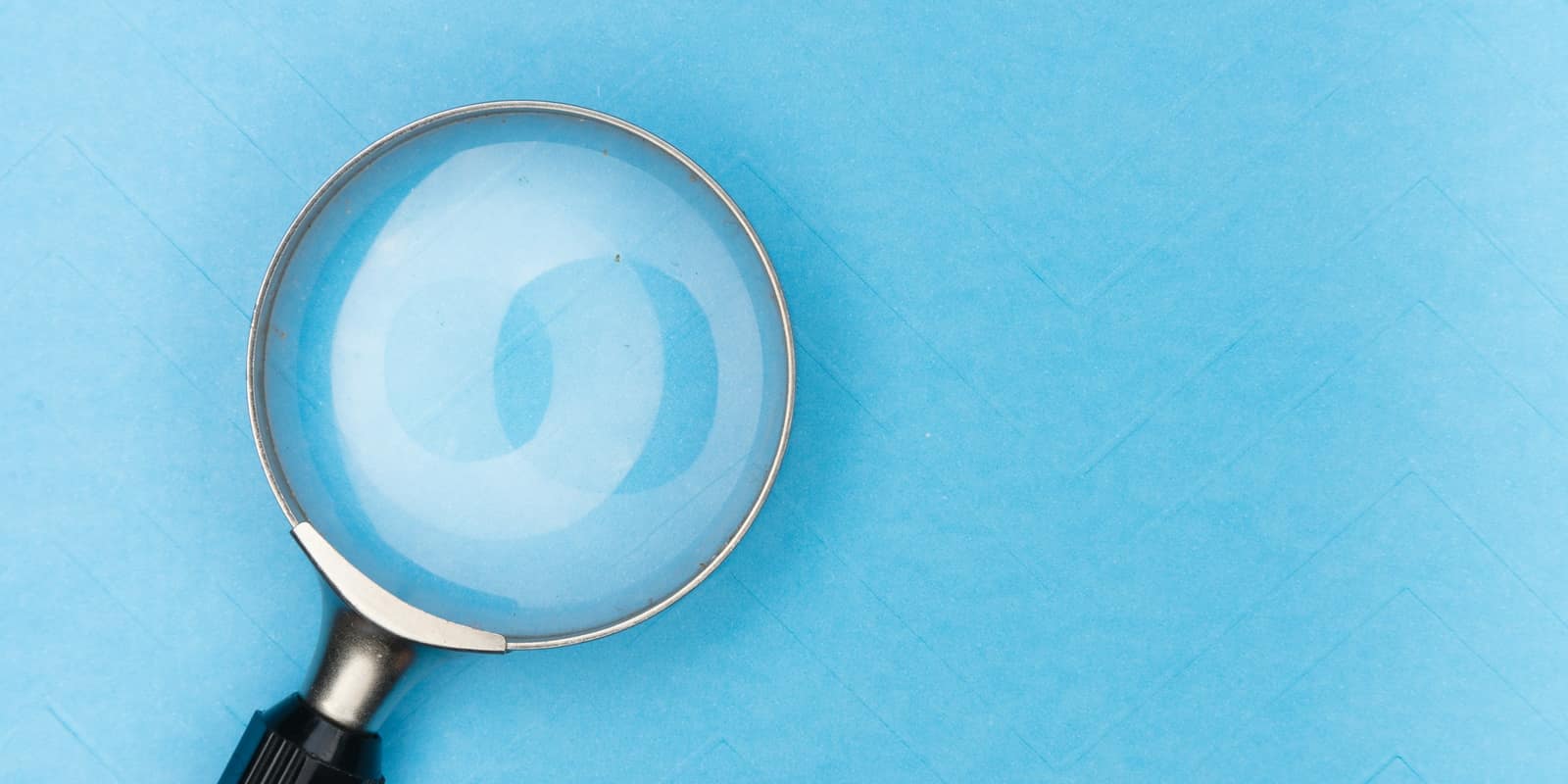 A magnifying glass lying on a light blue surface
